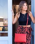 Woman holding a red bag, standing in front of a blue door.