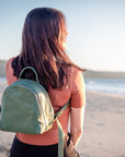 Woman with a green backpack standing on a beach