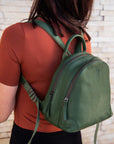 Person wearing a green backpack against a stone wall background
