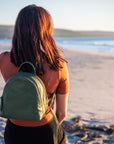 Person with a green backpack standing on a beach