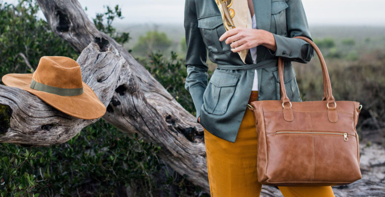 Person holding a brown leather bag with a scenic background