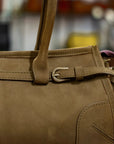 Brown leather handbag with a strap and buckle on a blurred background