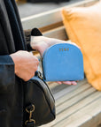 Person holding a blue wallet with 'Zemp' branding on a wooden bench.