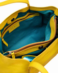 Yellow handbag with open front pocket showing teal interior