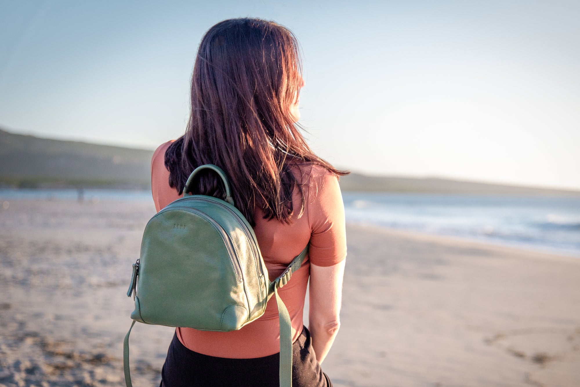 Woman with a green backpack standing on a beach