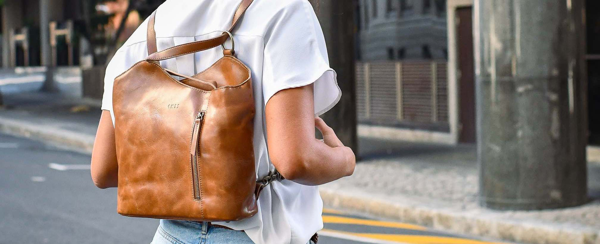 Person wearing a brown leather backpack on a city street