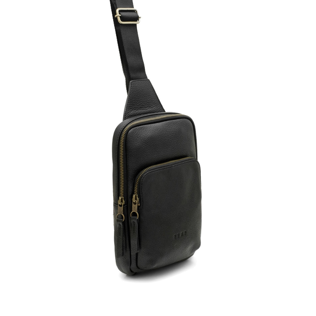 Black leather crossbody bag with gold zippers on a white background