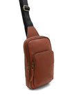 Brown leather sling bag with a black strap on a white background