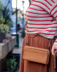 Person wearing a striped sweater and brown skirt with a tan crossbody bag in an outdoor setting