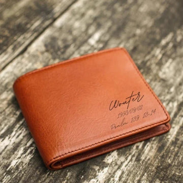 Brown leather wallet with engraved text on a wooden surface