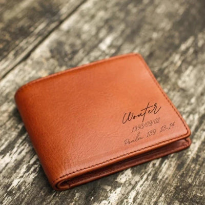 Brown leather wallet with engraved text on a wooden surface