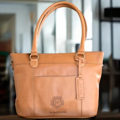Brown leather handbag with visible branding on a blurred indoor background