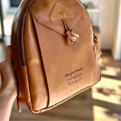 Brown leather backpack held by a person indoors