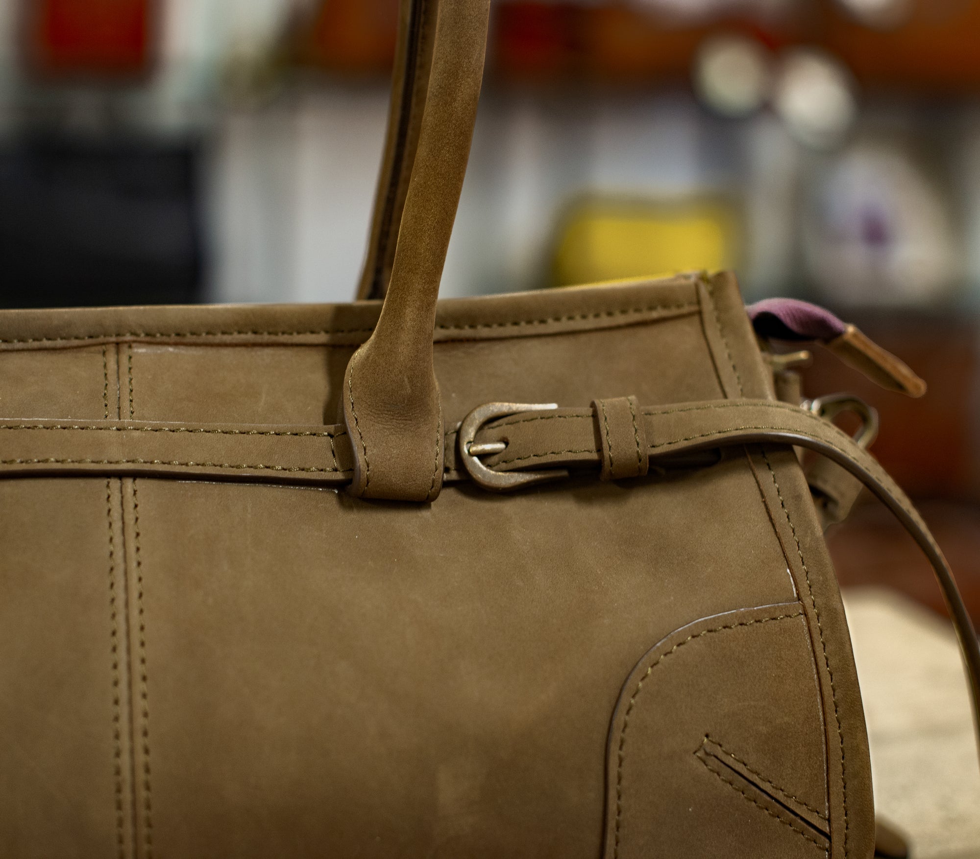 Brown leather handbag with a strap and buckle on a blurred background