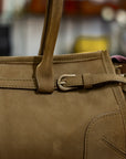 Brown leather handbag with a strap and buckle on a blurred background