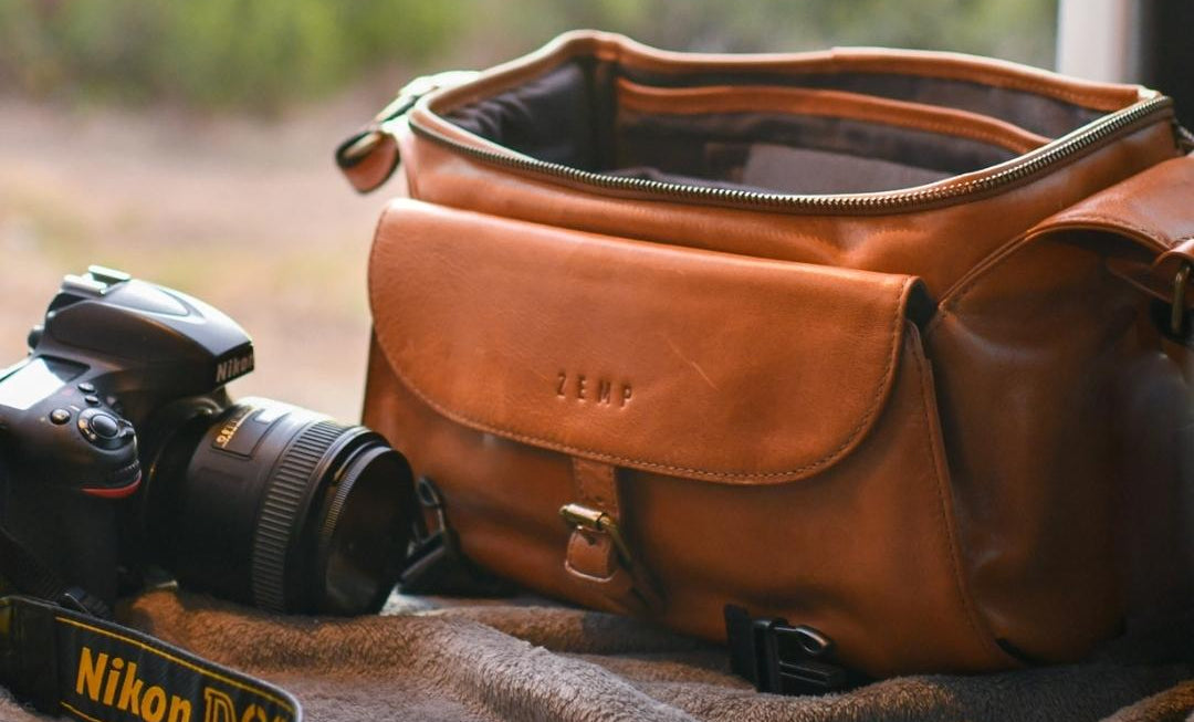 Brown leather camera bag with a Nikon camera on a natural background