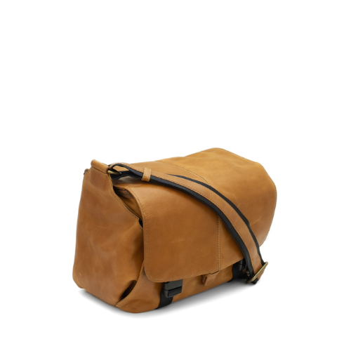 Brown leather bag with black strap on a white background
