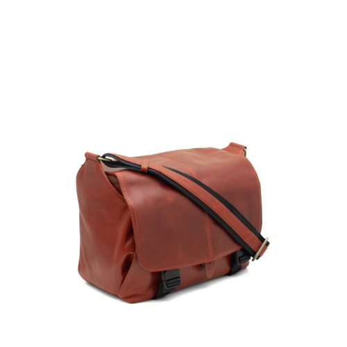 Brown leather bag with a black strap on a white background