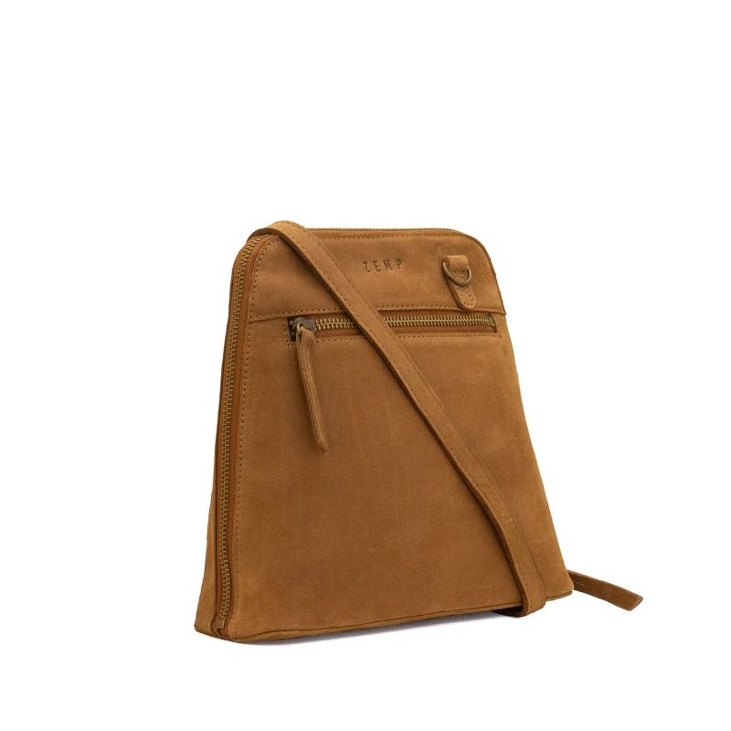 A tan suede crossbody bag with a front zippered pocket and a top zipper, shown on a plain white background.