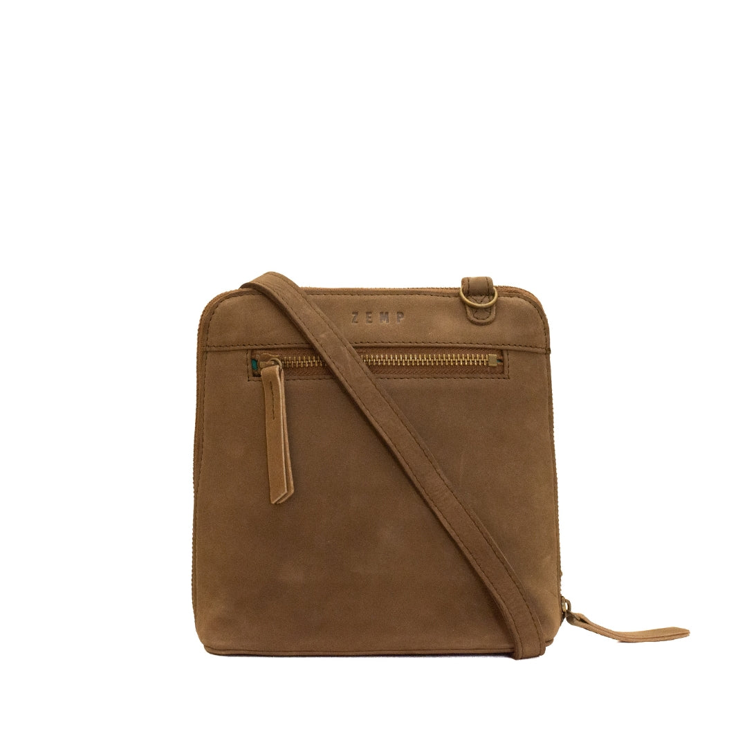 A brown suede crossbody bag with a matching leather strap, front zippered pocket, and a debossed 'CEMP' logo on the front, shown against a plain white background.