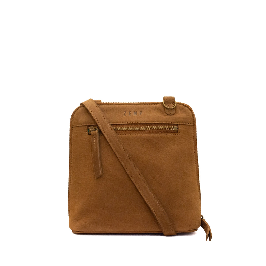 A tan suede crossbody bag with a matching leather strap, featuring a front zippered pocket and the brand name 'ZEMP' embossed on the top, set against a plain white background.