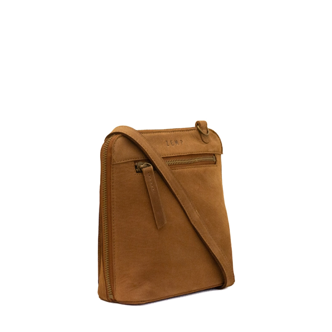 A tan leather crossbody bag with a matching leather strap and a front zippered pocket, shown on a plain white background.