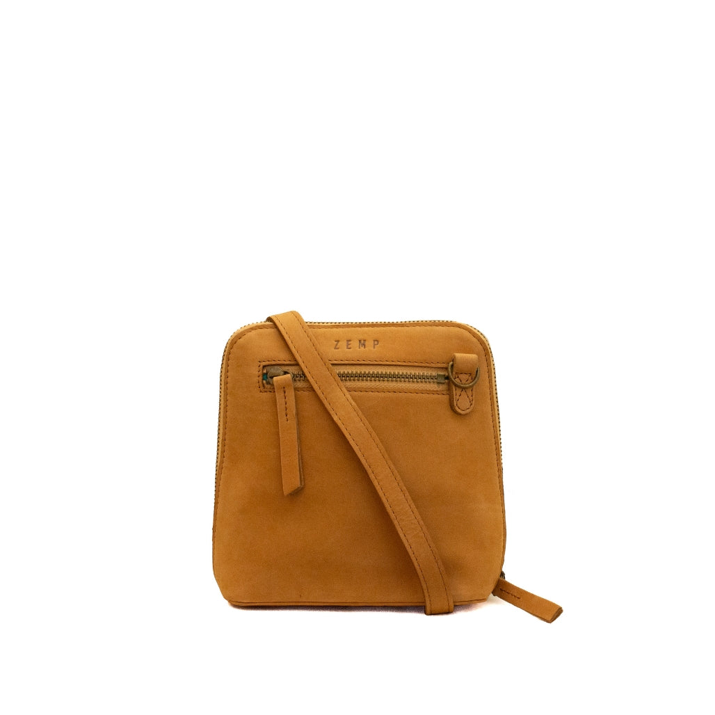 A small square crossbody bag in tan suede-like material with a matching shoulder strap, a front zip pocket, and the brand name 'ZEMP' embossed on the front, shown against a plain white background.