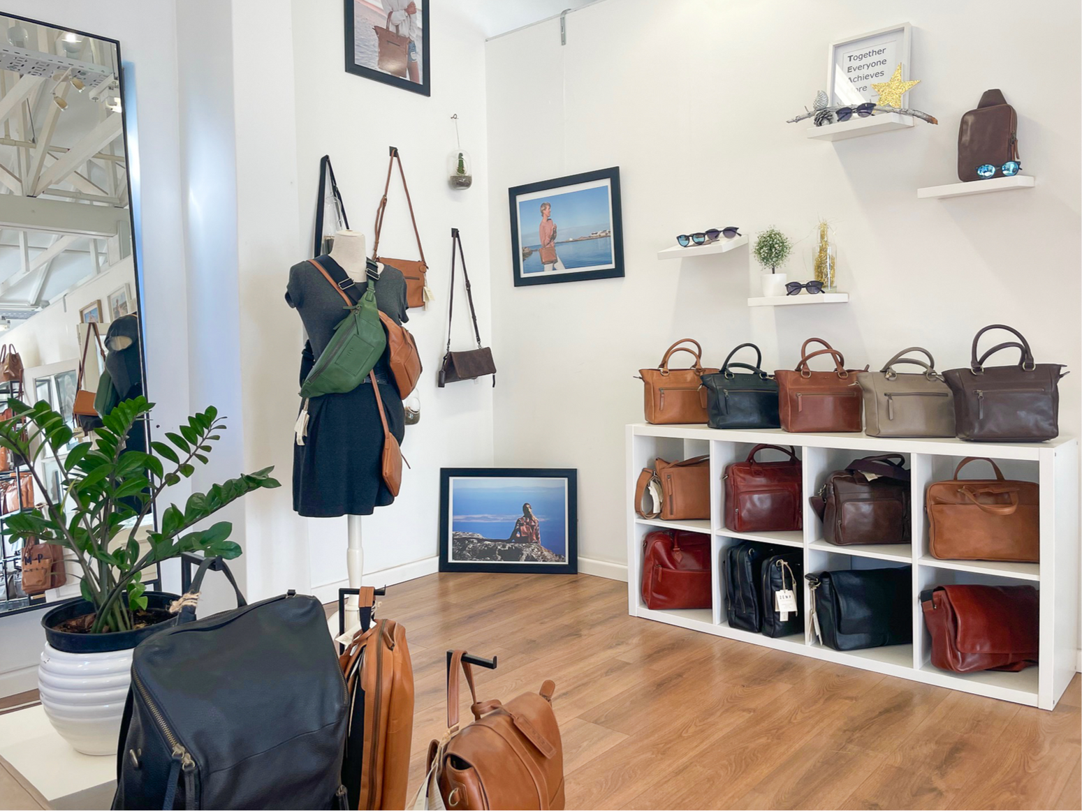 Display of handbags in a store with shelves and wall hangings.
