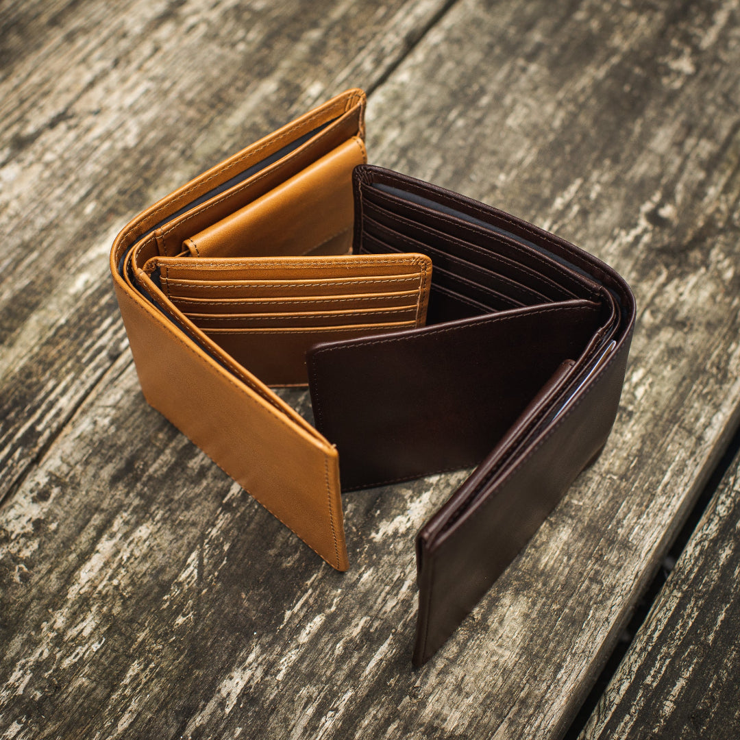 Two brown leather wallets on a wood table  - James 