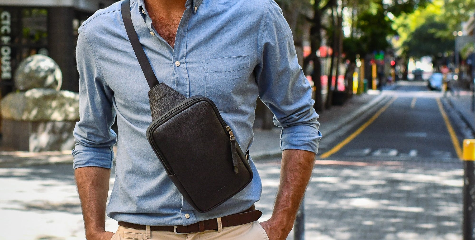 Man with a crossbody bag standing on a city street