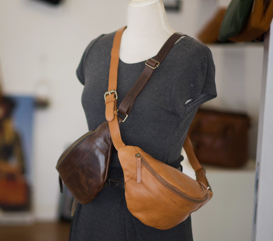 Brown leather crossbody bag on a mannequin with a blurred indoor background