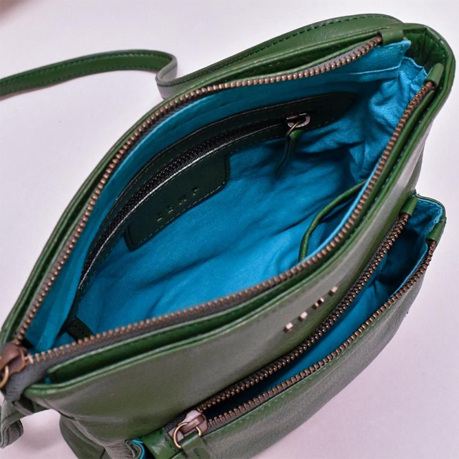 Green handbag with open zipper showing blue interior on a white background
