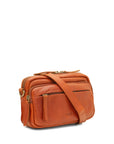 A warm chestnut leather crossbody bag with a matching leather shoulder strap, gold-tone hardware, and a front zippered pocket, shown on a plain white background.
