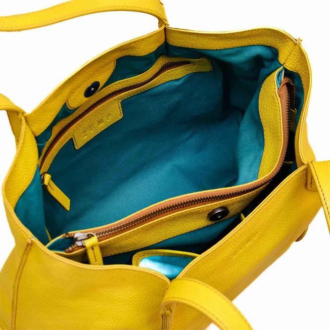 Yellow handbag with open front pocket showing teal interior