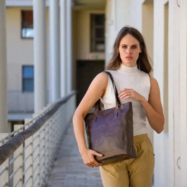 Woman holding a brown tote bag on a balcony