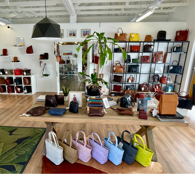 Interior of a store with various handbags displayed on shelves and tables.