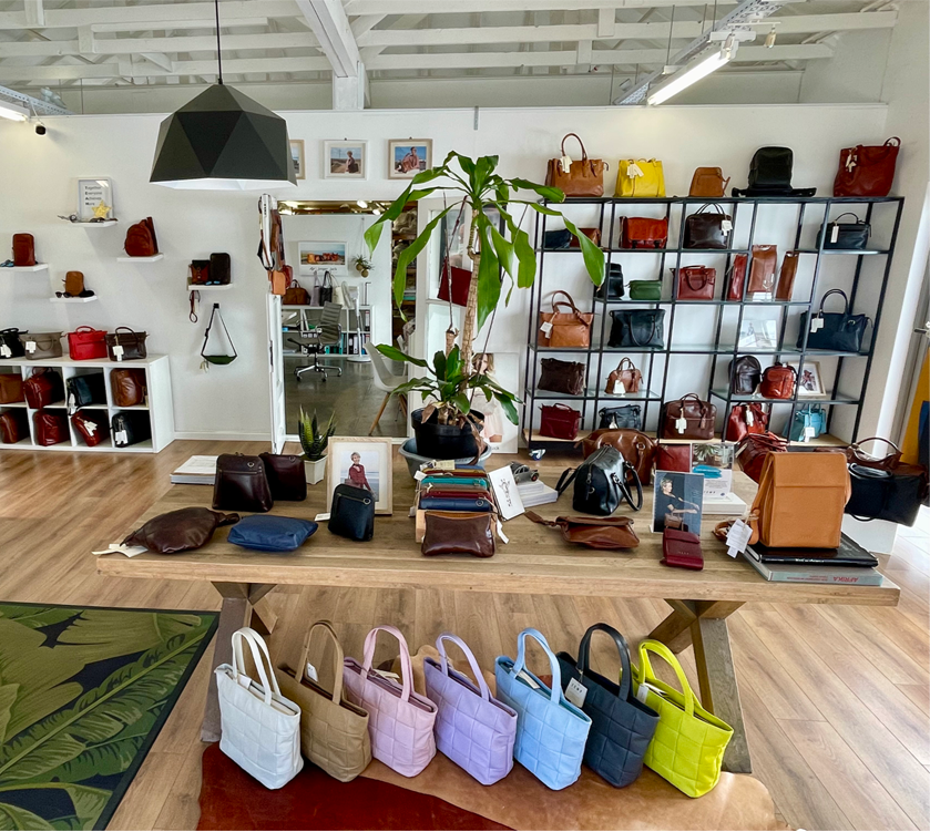 Interior of a store with various handbags displayed on shelves and tables.