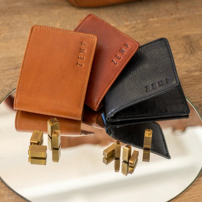 Three leather wallets in brown, black, and tan on a reflective surface with 'Zerm' branding.